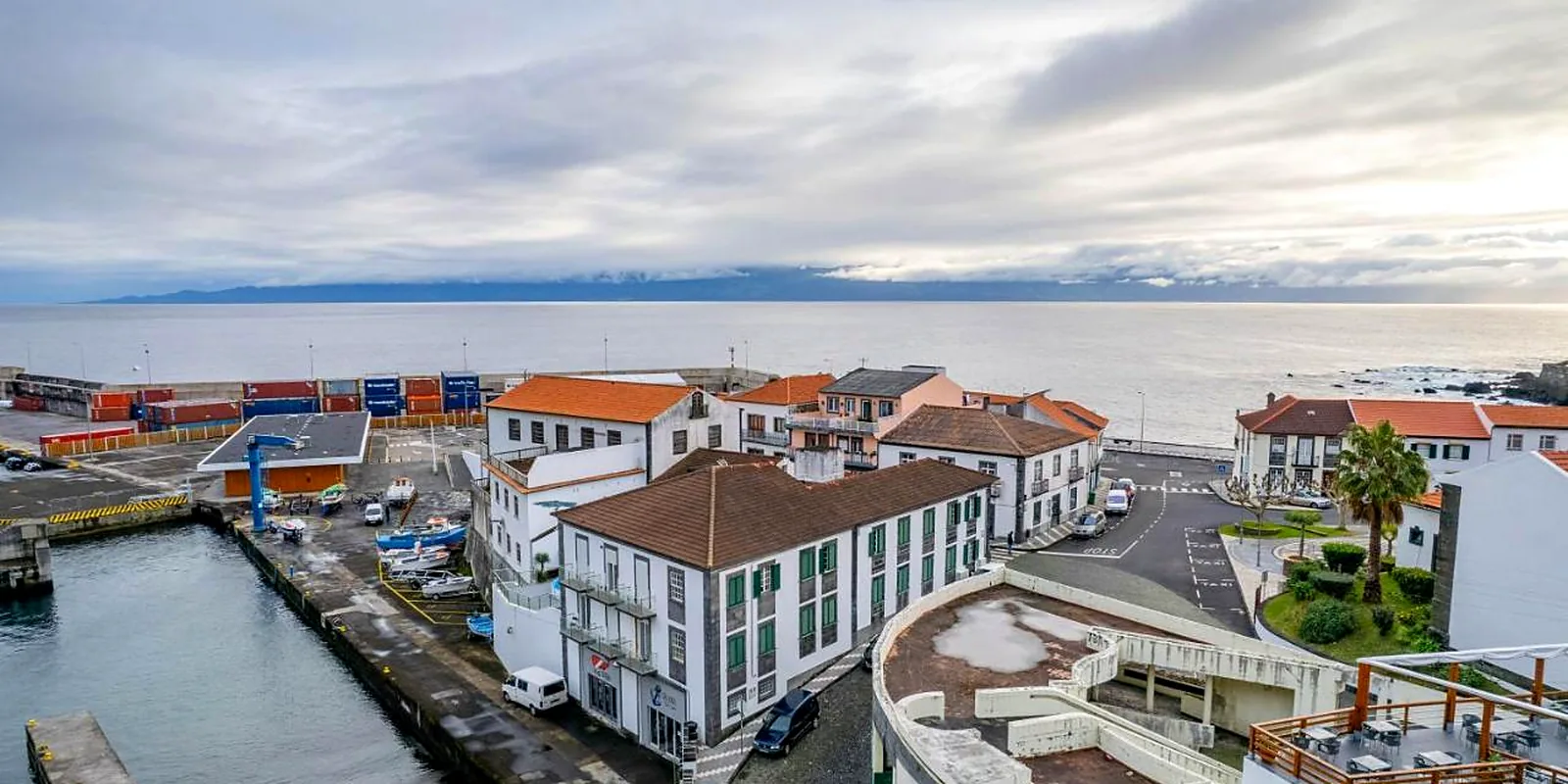 Vista aérea da vila e do porto das Velas, com o canal e a ilha do Pico ao fundo